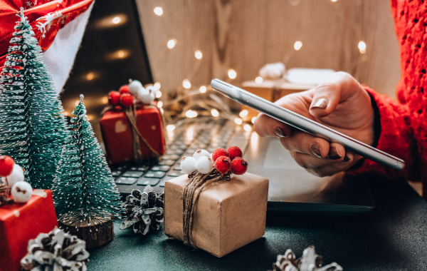 Photo of a scene showing Christmas decor. On the right, you see a woman's hand holding a smart phone