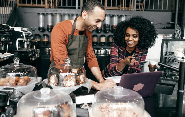 A woman and a man in front of a tablet in a bakery