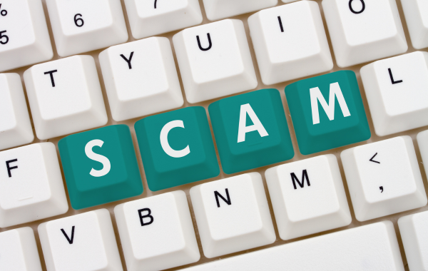 photo of a computer keyboard with the words SCAM shown prominently in the middle row of displayed keys